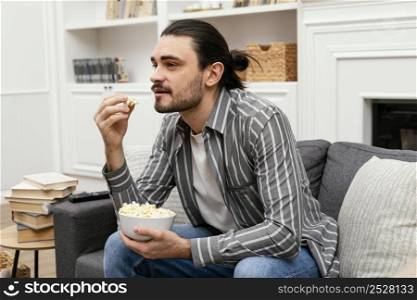 man eating popcorn watching tv couch