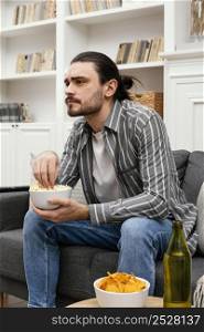 man eating popcorn watching tv side view
