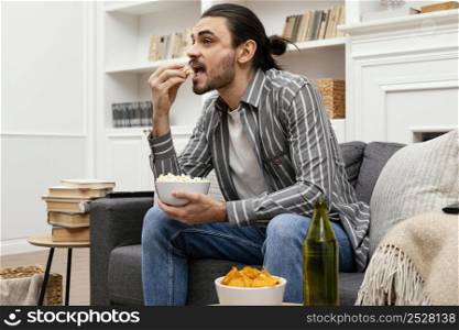 man eating popcorn watching tv sofa
