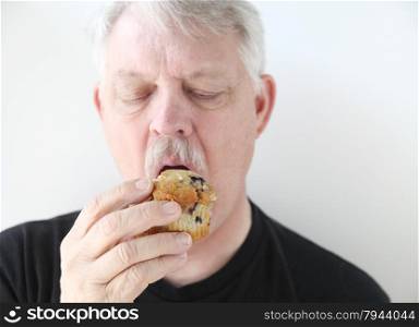 Man eats a fruit muffin.