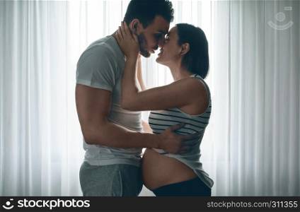 Man embracing and kissing his pregnant woman. Man embracing and kissing pregnant