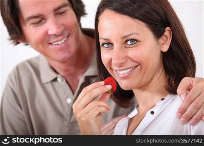 man embracing his wife while she is eating strawberries