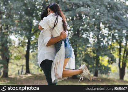 Man Embracing Woman While Standing On Grassy Field At Park