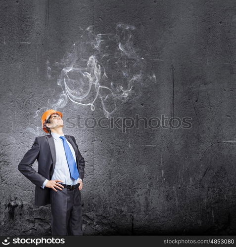 Man engineer. Thoughtful man in hardhat against city background