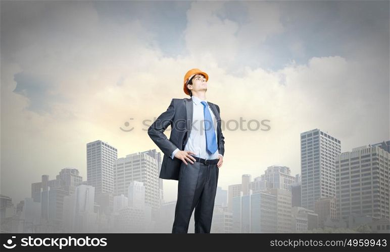 Man engineer. Thoughtful man in hardhat against city background