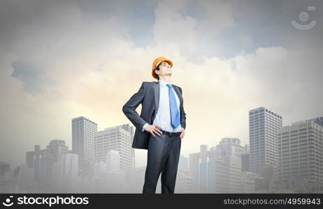 Man engineer. Thoughtful man in hardhat against city background