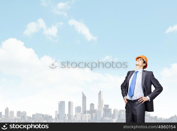 Man engineer. Thoughtful man in hardhat against city background