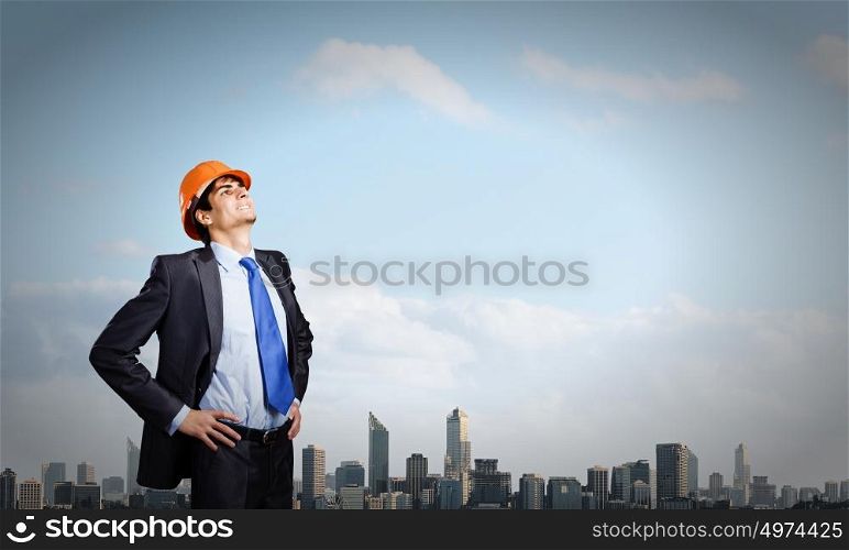 Man engineer. Thoughtful man in hardhat against city background