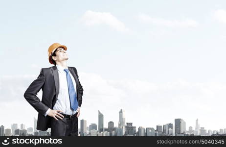 Man engineer. Thoughtful man in hardhat against city background