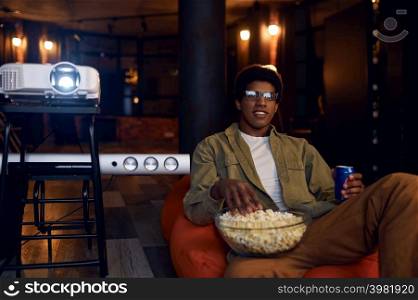 Man enjoy watching film using video projector. Young guy rest eating popcorn drinking soda. Man enjoy watching film using video projector