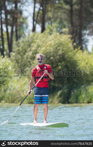 man enjoying a ride on the lake with paddleboard