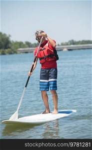 man enjoying a ride on the lake with paddleboard