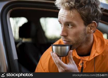 man enjoying hot beverage cup while road trip
