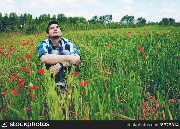 Man enjoying the day in a field of green wheat and flowers