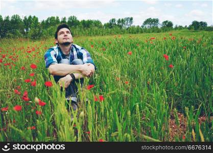 Man enjoying the day in a field of green wheat and flowers