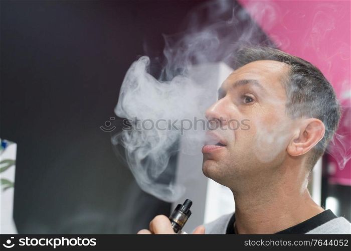 man enveloped in cloud of smoke from electronic cigarette