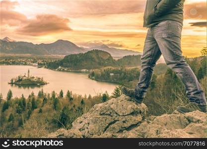 Man equipped with hiking shoes climbed on rocks above the lake Bled from Slovenia, in a December morning day