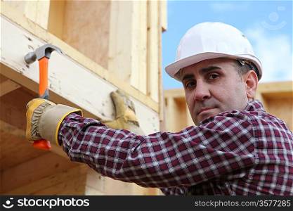 Man erecting wooden house