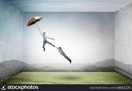 Man escaping on umbrella. Man trying to catch another who flying on colorful umbrella