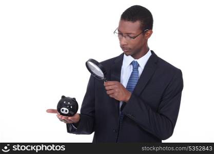 Man examining piggy bank with a magnifying glass