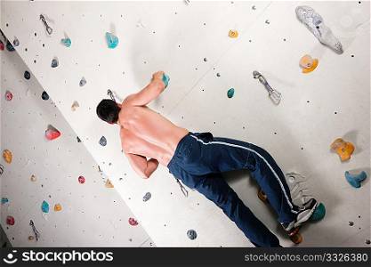 Man exercising at a climbing wall in a gym