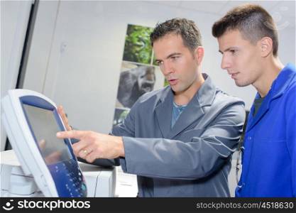 Man explaining controls of machine to apprentice