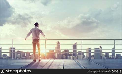 Man facing new day. Man boss standing on building top and looking at city