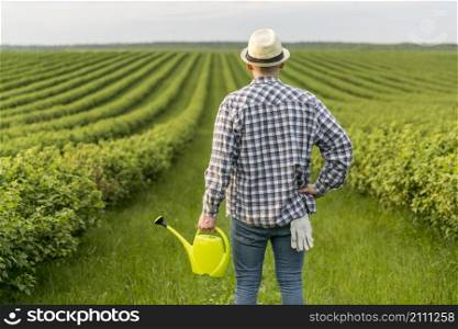 man farmland with watering can