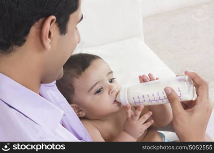 Man feeding baby with milk from bottle