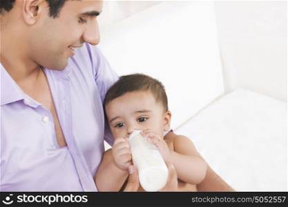 Man feeding baby with milk from bottle