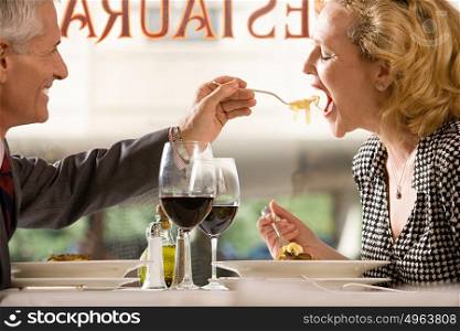 Man feeding pasta to woman