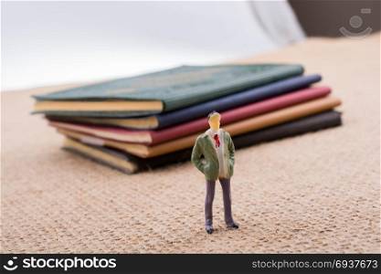 Man figurine standing beside little books on canvas