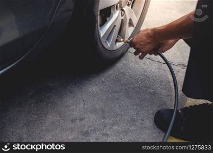 Man filling Air into the Tire. Car Driver Checking Air Pressure and Maintenance his Car by himself before Traveling