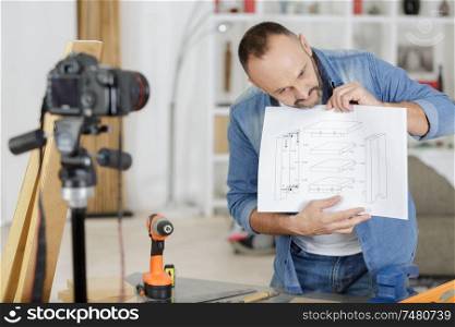 man filming himself holding cupboard assembling instructions
