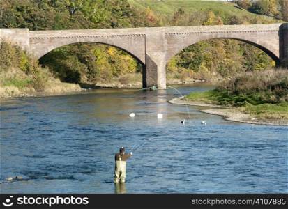 Man fishing in waders at bridge in Berwickshire, Scotland