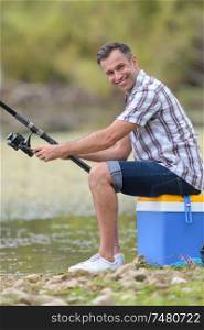 man fishing sat on cool-box