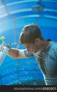 Man fitness runner drinking and splashing water in his face. Funny image of handsome male refreshing during workout