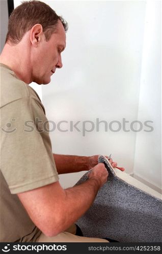 Man fitting carpet into the corner of a room