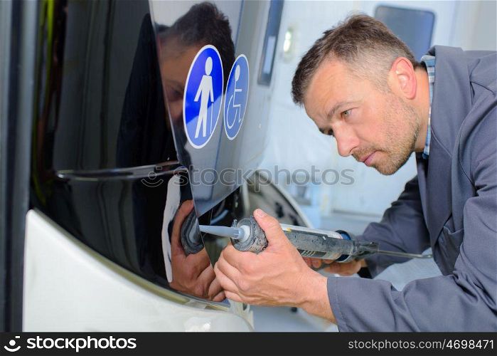 Man fitting panel to bus
