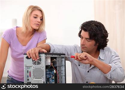 man fixing computer with woman watching