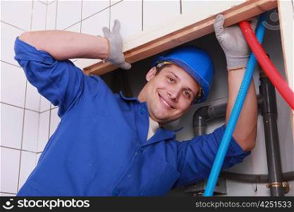 Man fixing plumbing in bathroom