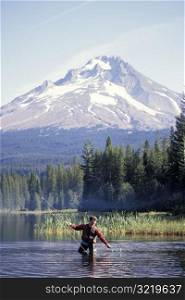 Man Fly Fishing in Front of Mountain