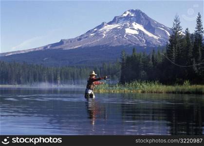 Man Fly Fishing In Mountain Lake
