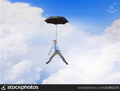 Man fly on umbrella. Young businessman flying high in sky on umbrella