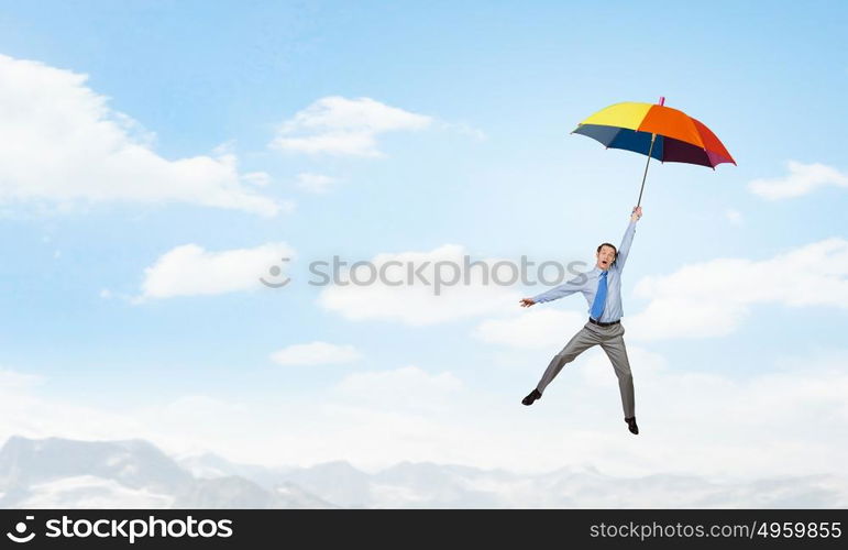 Man fly on umbrella. Young businessman flying high in sky on umbrella