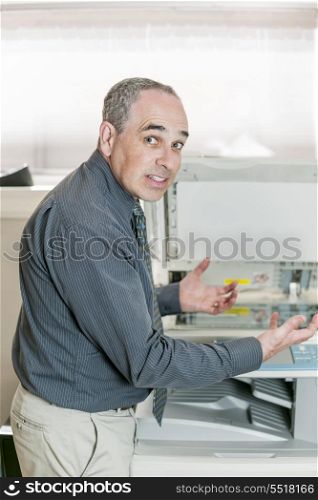 Man frustrated with photocopier. Business man having problem with photocopy machine in office looking frustrated and angry