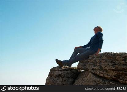 Man gesturing on the rock with blue background