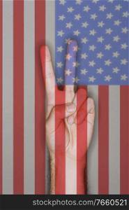 Man gesturing peace sign against american flag