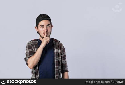 Man gesturing to keep quiet, guy with finger on mouth showing hush gesture, hush please concept