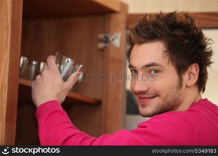 Man getting a glass out of the cupboard